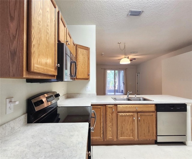 kitchen featuring stainless steel appliances, kitchen peninsula, sink, and a textured ceiling