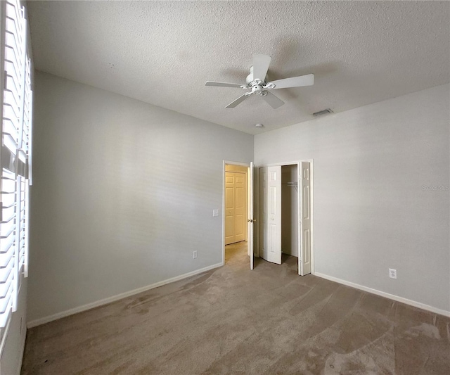 unfurnished bedroom with ceiling fan, a closet, a textured ceiling, and carpet