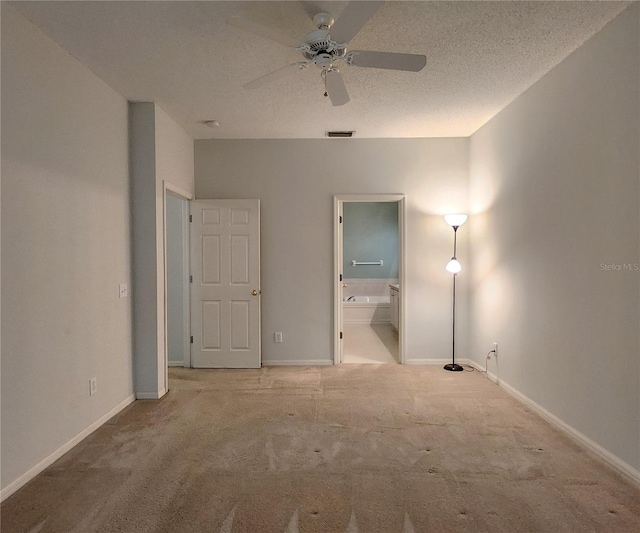 unfurnished bedroom with connected bathroom, light colored carpet, a textured ceiling, and ceiling fan