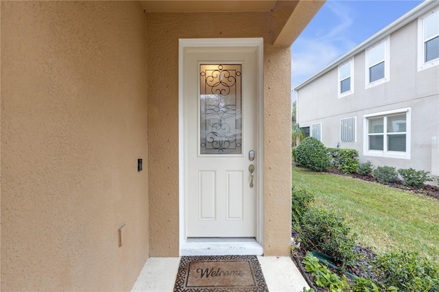 doorway to property with a lawn