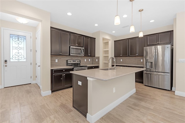 kitchen with sink, dark brown cabinets, hanging light fixtures, a center island with sink, and stainless steel appliances