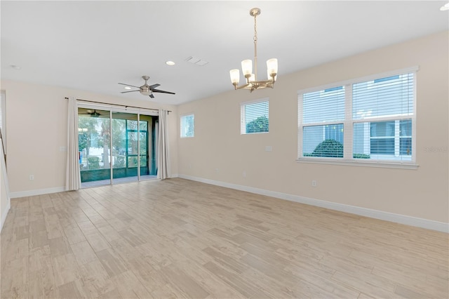 spare room with ceiling fan with notable chandelier and light hardwood / wood-style flooring