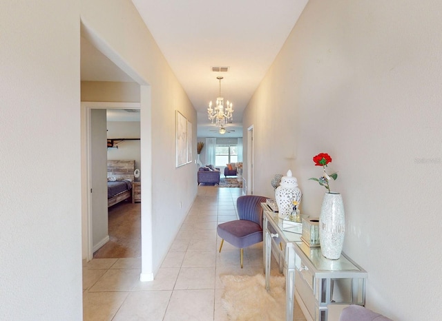 hall with light tile patterned flooring and a chandelier