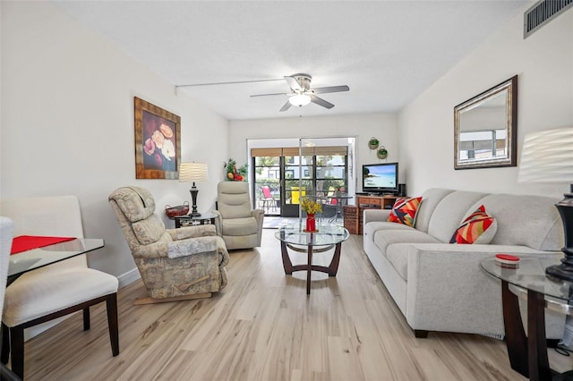 living room featuring a textured ceiling, light hardwood / wood-style flooring, and ceiling fan