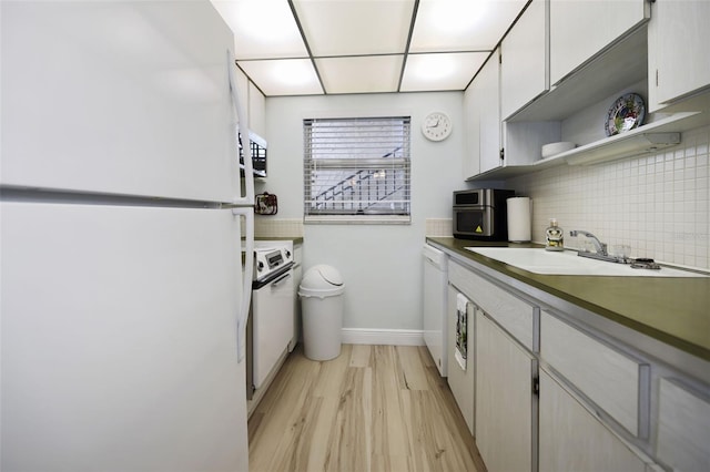 kitchen featuring white cabinetry, white appliances, sink, and backsplash