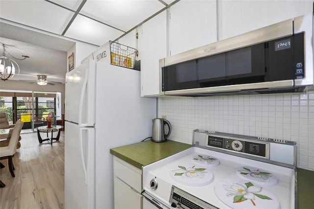 kitchen featuring white cabinetry, tasteful backsplash, light wood-type flooring, white fridge, and stove