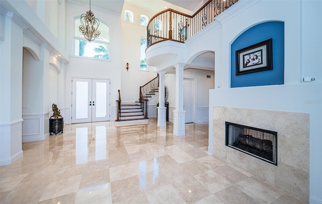 entrance foyer with decorative columns, crown molding, a chandelier, and french doors