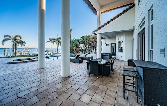 view of patio with a swimming pool with hot tub, an outdoor living space, an outdoor bar, and a water view