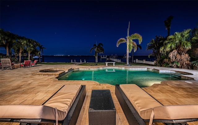 pool at twilight featuring an in ground hot tub, a water view, and a patio area