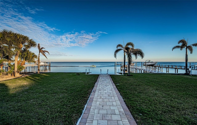 view of dock with a lawn and a water view