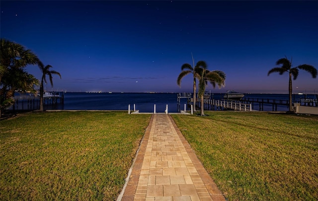 view of dock with a water view and a yard