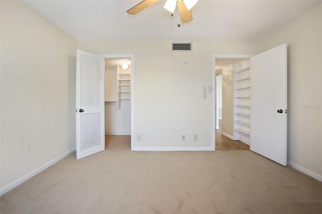 unfurnished bedroom featuring ceiling fan, light colored carpet, a spacious closet, and a closet