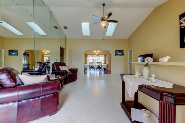 living room with light tile patterned floors, a skylight, high vaulted ceiling, and ceiling fan