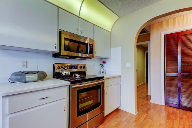 kitchen featuring stainless steel appliances, light hardwood / wood-style flooring, and white cabinets