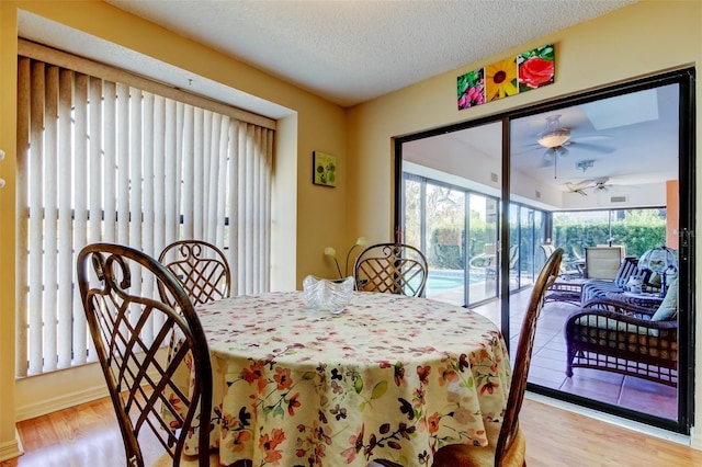 dining space with ceiling fan, a textured ceiling, and light hardwood / wood-style floors