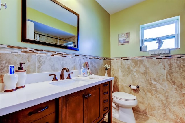 bathroom with tile patterned floors, vanity, toilet, and tile walls