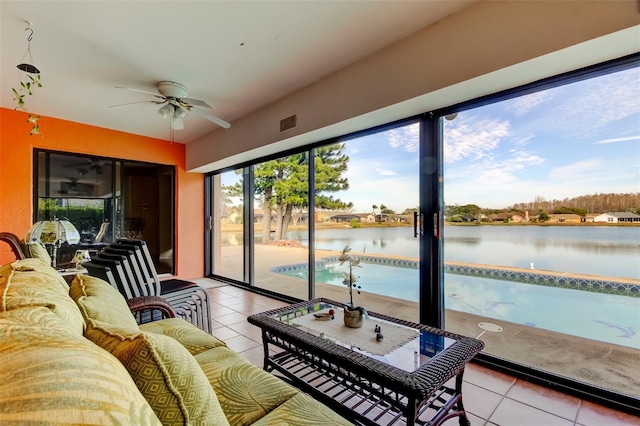 living room featuring a water view, ceiling fan, and light tile patterned floors