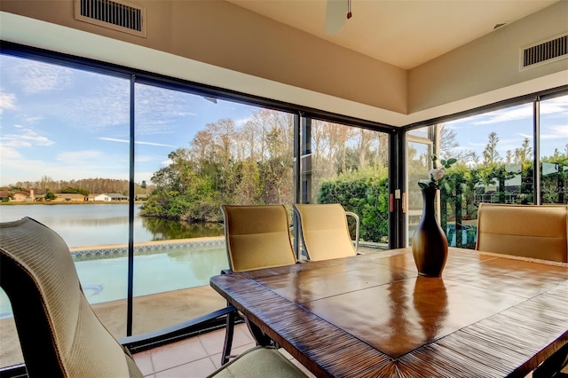 unfurnished sunroom with ceiling fan and a water view