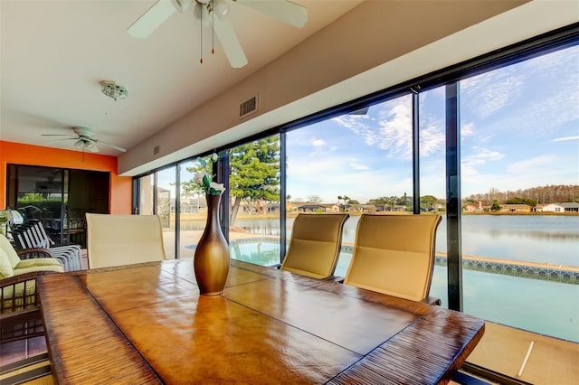 sunroom / solarium featuring a water view and ceiling fan