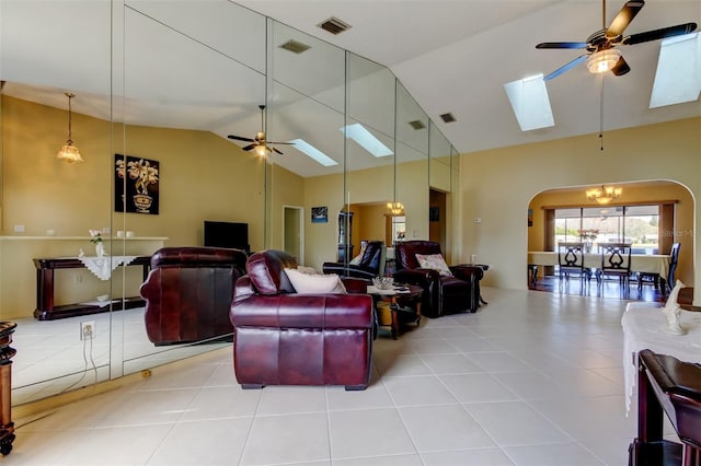 tiled living room featuring a skylight, arched walkways, and ceiling fan
