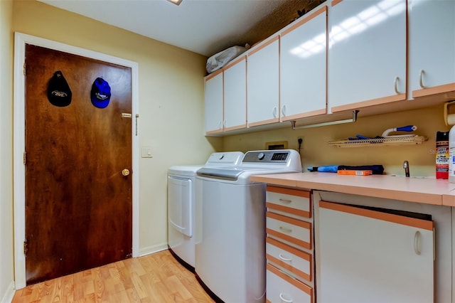 laundry area featuring cabinet space, washer and dryer, and light wood-style flooring