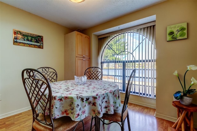 dining space featuring light wood-style flooring, a healthy amount of sunlight, and baseboards