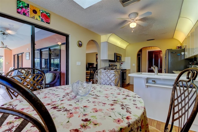 bedroom with visible vents, arched walkways, freestanding refrigerator, a textured ceiling, and access to outside