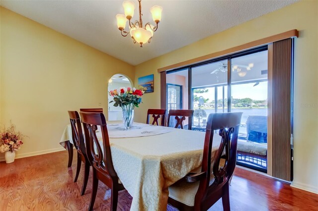 dining space featuring baseboards, lofted ceiling, an inviting chandelier, and wood finished floors
