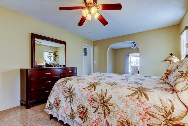 bedroom with ceiling fan, baseboards, arched walkways, and a textured ceiling