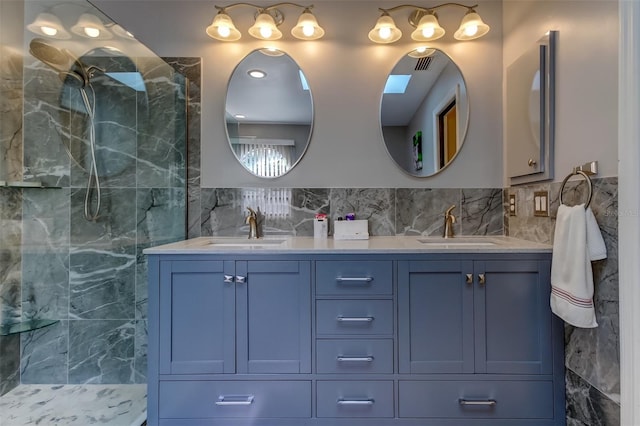full bathroom with a sink, tiled shower, tile walls, and double vanity