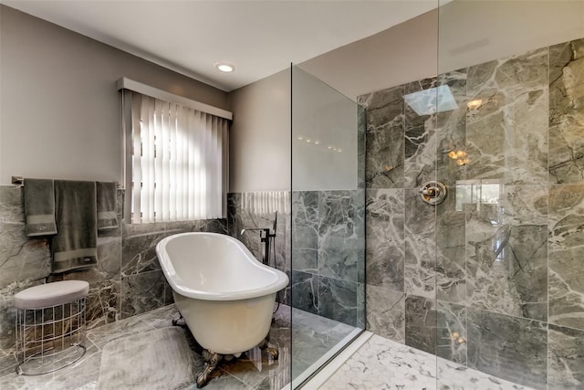 bathroom featuring walk in shower, a wainscoted wall, a freestanding bath, marble finish floor, and tile walls