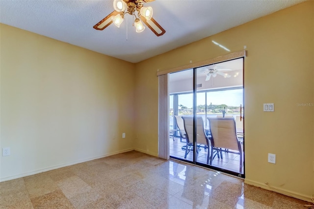 spare room featuring granite finish floor, ceiling fan, and baseboards