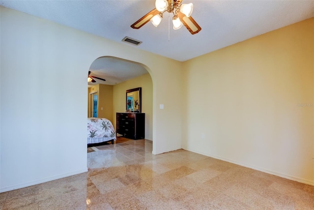 unfurnished bedroom with a ceiling fan, visible vents, arched walkways, and baseboards