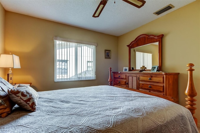 bedroom featuring visible vents, lofted ceiling, a textured ceiling, and ceiling fan