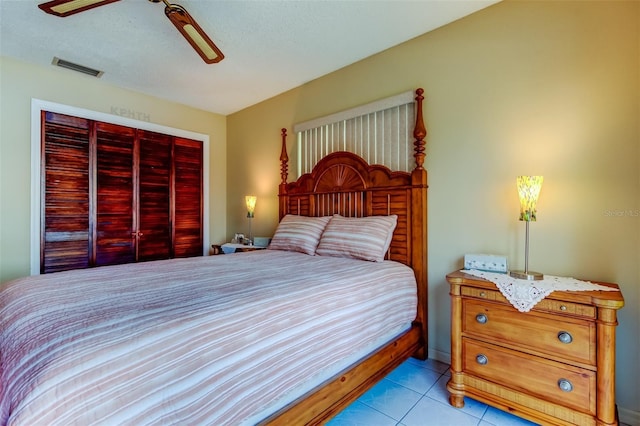 bedroom with a ceiling fan, light tile patterned flooring, visible vents, and a closet