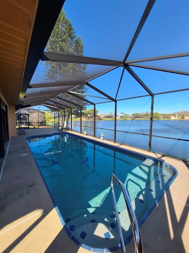 outdoor pool featuring glass enclosure, a patio area, and a water view