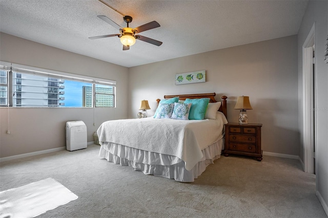 bedroom featuring ceiling fan, light colored carpet, and a textured ceiling