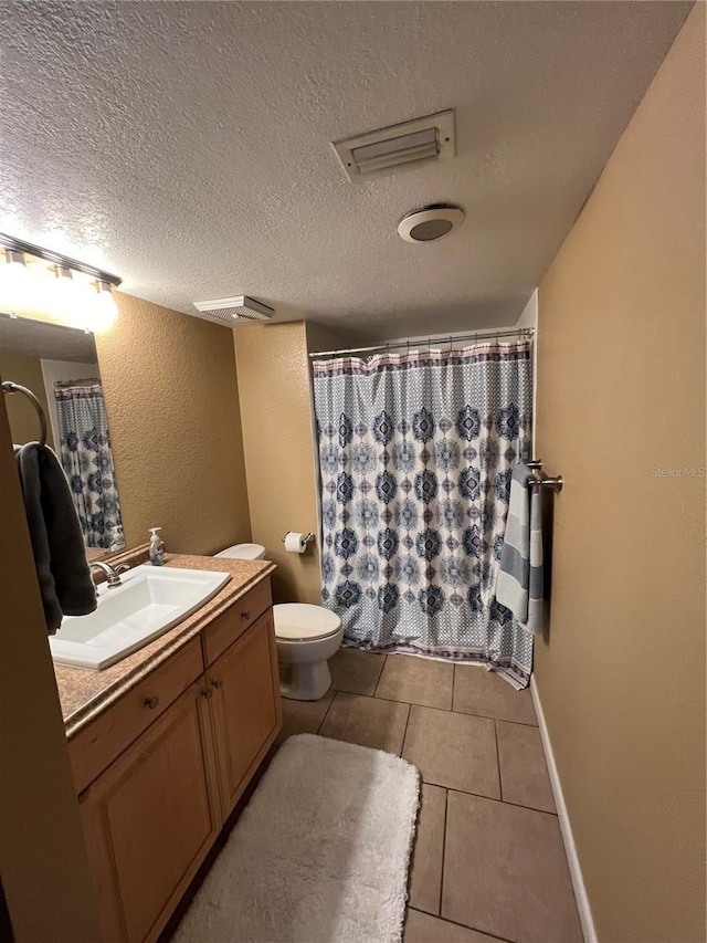 bathroom with tile patterned flooring, vanity, a textured ceiling, and toilet