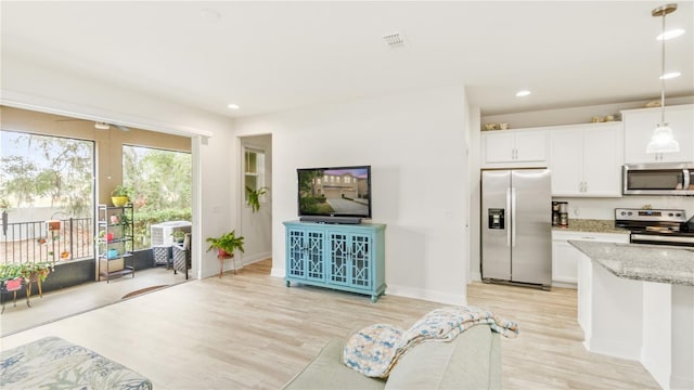 kitchen featuring pendant lighting, light stone countertops, white cabinets, and appliances with stainless steel finishes