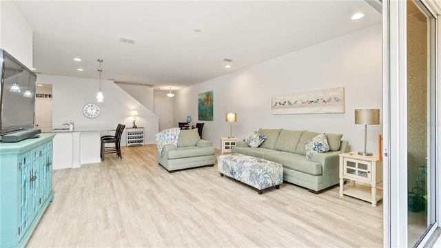 living room featuring sink and light hardwood / wood-style flooring