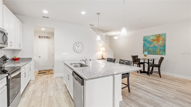 kitchen with a breakfast bar, white cabinetry, pendant lighting, stainless steel appliances, and a kitchen island with sink