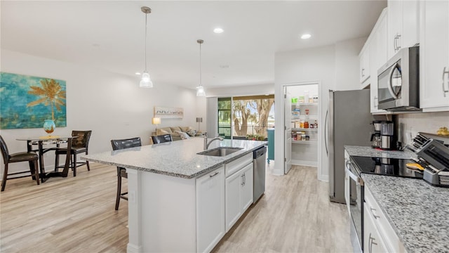 kitchen featuring sink, a breakfast bar area, a center island with sink, appliances with stainless steel finishes, and white cabinets