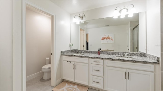 bathroom with tile patterned flooring, vanity, a shower with shower door, and toilet