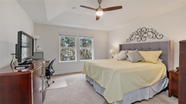 bedroom featuring light carpet, a tray ceiling, and ceiling fan