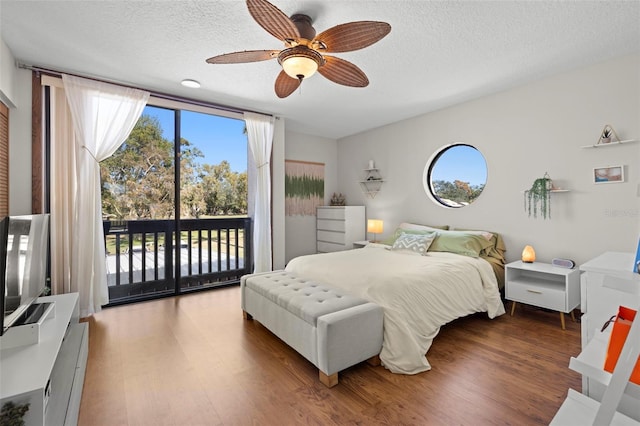 bedroom featuring dark wood-type flooring, access to outside, and a textured ceiling