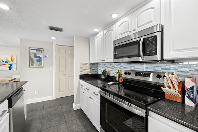 kitchen with appliances with stainless steel finishes, dark stone counters, decorative backsplash, and white cabinets