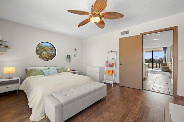 bedroom featuring dark hardwood / wood-style flooring, ceiling fan, and a textured ceiling