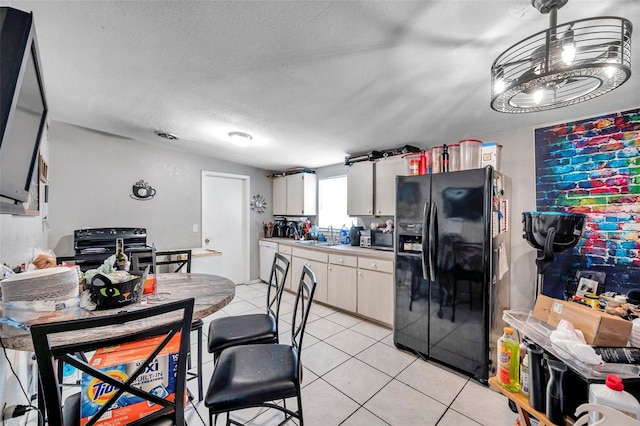 kitchen with a textured ceiling, black appliances, white cabinets, and light tile patterned flooring