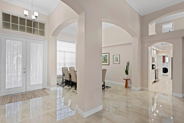 entryway featuring ornamental molding, washer / dryer, a notable chandelier, and french doors