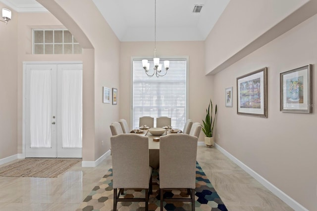 dining room with an inviting chandelier, a raised ceiling, and french doors